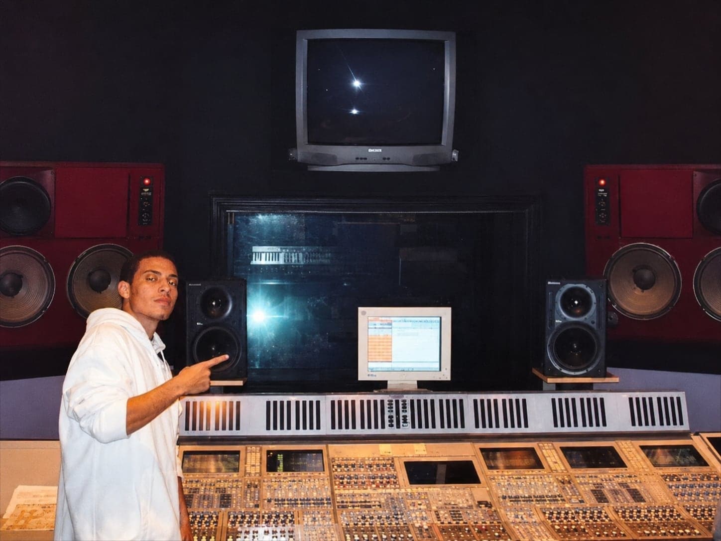 Abel J. Fernandez in a recording studio pointing toward the mixing console